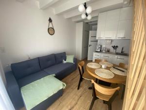 - un salon avec un canapé bleu et une table dans l'établissement SOLEK Apartamenty i pokoje gościnne, à Mielno