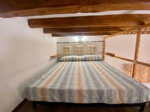 Ce lit se trouve dans un dortoir doté d'un plafond en bois. dans l'établissement Casa Labi, à Termini Imerese