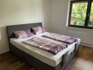 a bed with purple pillows on it in a room at Bungalow mit großem Garten uneinsehbar und Stellplatz in Landshut