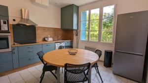 eine Küche mit einem Holztisch und Stühlen in der Unterkunft Les escales Périgourdines, Lucie, 3 étoiles in Trémolat