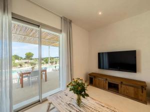 a living room with a tv and a sliding glass door at Casa Casita in Cala Saona