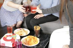 two people sitting on a couch with drinks and food at ZONK HOTEL Haruyoshi-Teramachidori in Fukuoka
