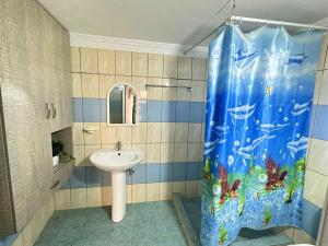 baño con lavabo y cortina de ducha en Boungainvillea, en Himare