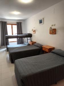 a hotel room with three beds and a window at HOTEL FAMILIAR MAXIMINA in Sallent de Gállego