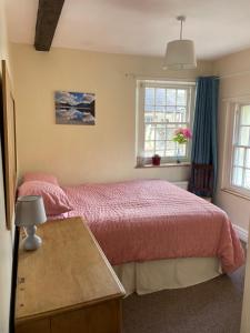 a bedroom with a bed and a table and windows at Robinsons Cottage, central and quiet in Cockermouth
