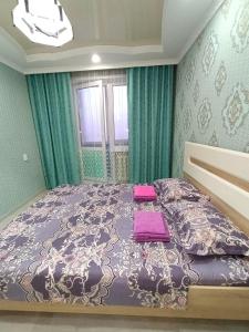 1 dormitorio con 1 cama grande y edredón morado en Апартаменты формата Люкс в Центре г.Семей, en Semey