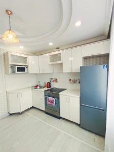 a kitchen with white cabinets and a blue refrigerator at Апартаменты формата Люкс в Центре г.Семей in Semey