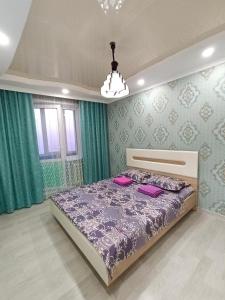een slaapkamer met een bed met roze kussens erop bij Апартаменты формата Люкс в Центре г.Семей in Semey
