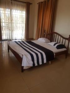 sypialnia z łóżkiem z czarno-białym kocem o paskach w obiekcie Naalya Estate House w mieście Kampala