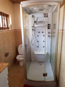 a glass shower in a bathroom with a toilet at Naalya Estate House in Kampala