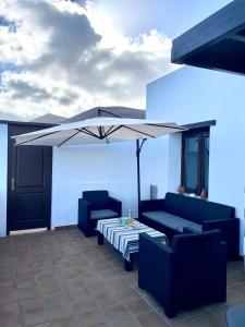 a patio with two chairs and a table and an umbrella at Canto Rojo, La Asomada con vistas a Lobos in La Asomada