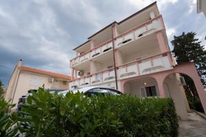 a building with a car parked in front of it at Apartmani Vidušin in Novalja