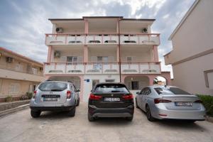 two cars parked in front of a building at Apartmani Vidušin in Novalja