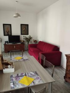 Appartamento Miro في سان بيليغرينو تيرمي: غرفة معيشة مع أريكة حمراء وطاولة