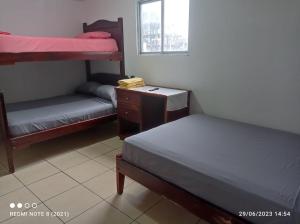 a bedroom with two bunk beds and a desk and a window at Hostal SAMARY in Atacames