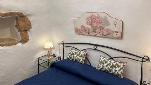 a bedroom with a bed with blue sheets and a lamp at Trulli delle succulente in Capilungo