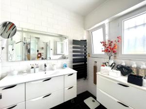 ein weißes Badezimmer mit einem Waschbecken und einem Spiegel in der Unterkunft Le 7 in Capbreton