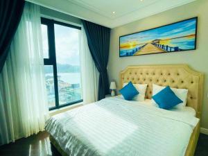 Un dormitorio con una cama con almohadas azules y una ventana en Căn hộ Altara 5 sao Quy Nhơn - Thiên Trang apartment en Quy Nhon
