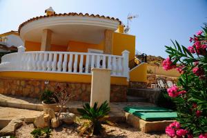 una casa amarilla con una escalera blanca y flores rosas en Villa Canamon en Mutxamel