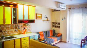 a kitchen with yellow cabinets and a couch and a sink at Nada SeaView Apartment in Shëngjin