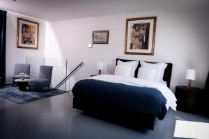 um quarto com uma cama preta e branca e uma cadeira em Suite Aux Anges em Antuérpia