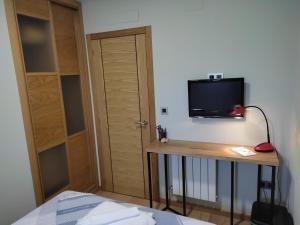 Zimmer mit einem Bett und einem TV an der Wand in der Unterkunft Home Barbaña in Ourense