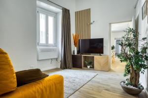 ein Wohnzimmer mit einem gelben Sofa und einem TV in der Unterkunft Grand Maison del Moro - Trastevere in Rom
