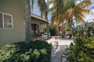 a house with a palm tree in front of it at Unbounded Horizons:Serene home with Panoramic view in Savaneta