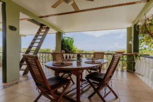 una mesa de madera y sillas en un balcón con una escalera en Unbounded Horizons:Serene home with Panoramic view, en Savaneta