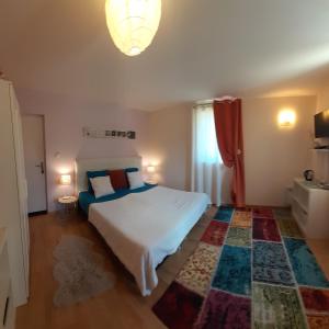 1 dormitorio con cama blanca y alfombra colorida en Les Terrasses du Paradis en Orpierre