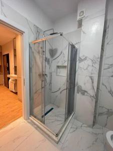 een badkamer met een douche en marmeren muren bij Comfort,excellence. in Kamëz