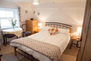 Schlafzimmer mit einem Bett, einem Tisch und einem Fenster in der Unterkunft The Cottage in Cross in Hand