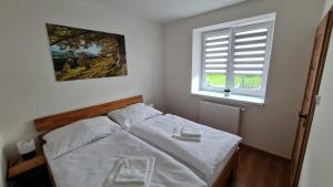 a bedroom with a bed with white sheets and a window at Horský apartmán Karlovice in Karlovice