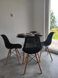 a table with four chairs in a room with a window at Modlinek 8a in Ustka