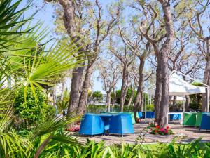 un groupe de tables de pique-nique bleues dans un parc arboré dans l'établissement Hotel Sporting, à San Benedetto del Tronto