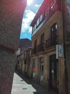 an alley with buildings and a person on a bike at Apartamentos & Rooms Santiaguiño in Padrón