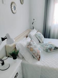 a white bed with pillows and a lamp on a table at JB House in Nazaré