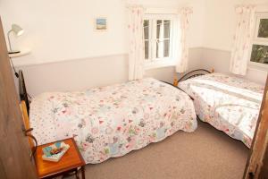 a bedroom with two beds and a table at The Cottage in Cross in Hand