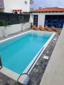 een zwembad met blauw water voor een huis bij Apartman Dawidh in Šibenik