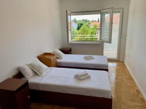 2 Betten in einem Zimmer mit Fenster in der Unterkunft Apartments Janko in Pakoštane