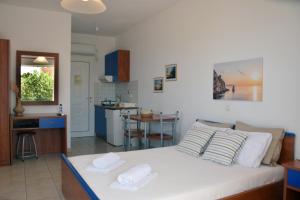 Lappas Rooms في روفيس: غرفة نوم بسرير ابيض ومطبخ