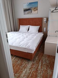 a bed in a small room with a white bedsheet at Bel Mare Aqua 2 and Garden F104 in Międzyzdroje