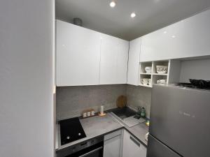 cocina con armarios blancos y nevera de acero inoxidable en Apartments San Monte en Podstrana