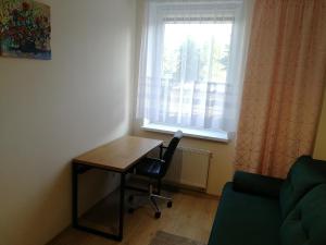 una scrivania e una sedia in una stanza con finestra di Apartament nad Węgorapą a Węgorzewo