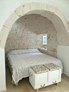 1 dormitorio con 1 cama en una pared de piedra en Trullollero UnPostoNelMondo, en Ceglie Messapica