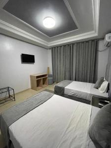 ein Hotelzimmer mit 2 Betten und einem TV in der Unterkunft Hotel la Perle d'Arfoud in Erfoud