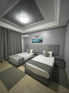 伊尔富德Hotel la Perle d'Arfoud的一间卧室，有两张床和一台挂在墙上的电视