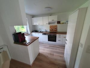 a kitchen with white cabinets and a wooden floor at Haus zur Sonne in Lindenberg im Allgäu