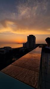 a person sitting on the edge of a balcony at sunset at Seven's Rooftop in Durrës