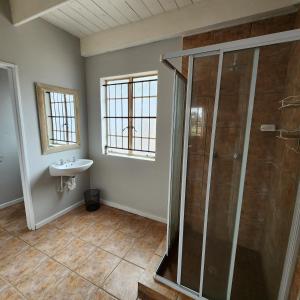 uma casa de banho com um chuveiro e um lavatório. em Karoo Leeu Cottage em Oudtshoorn